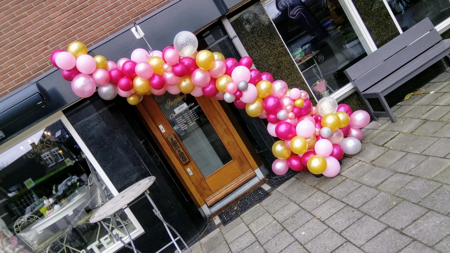Roze, gouden en witte organische ballondecoratie bij een voordeur