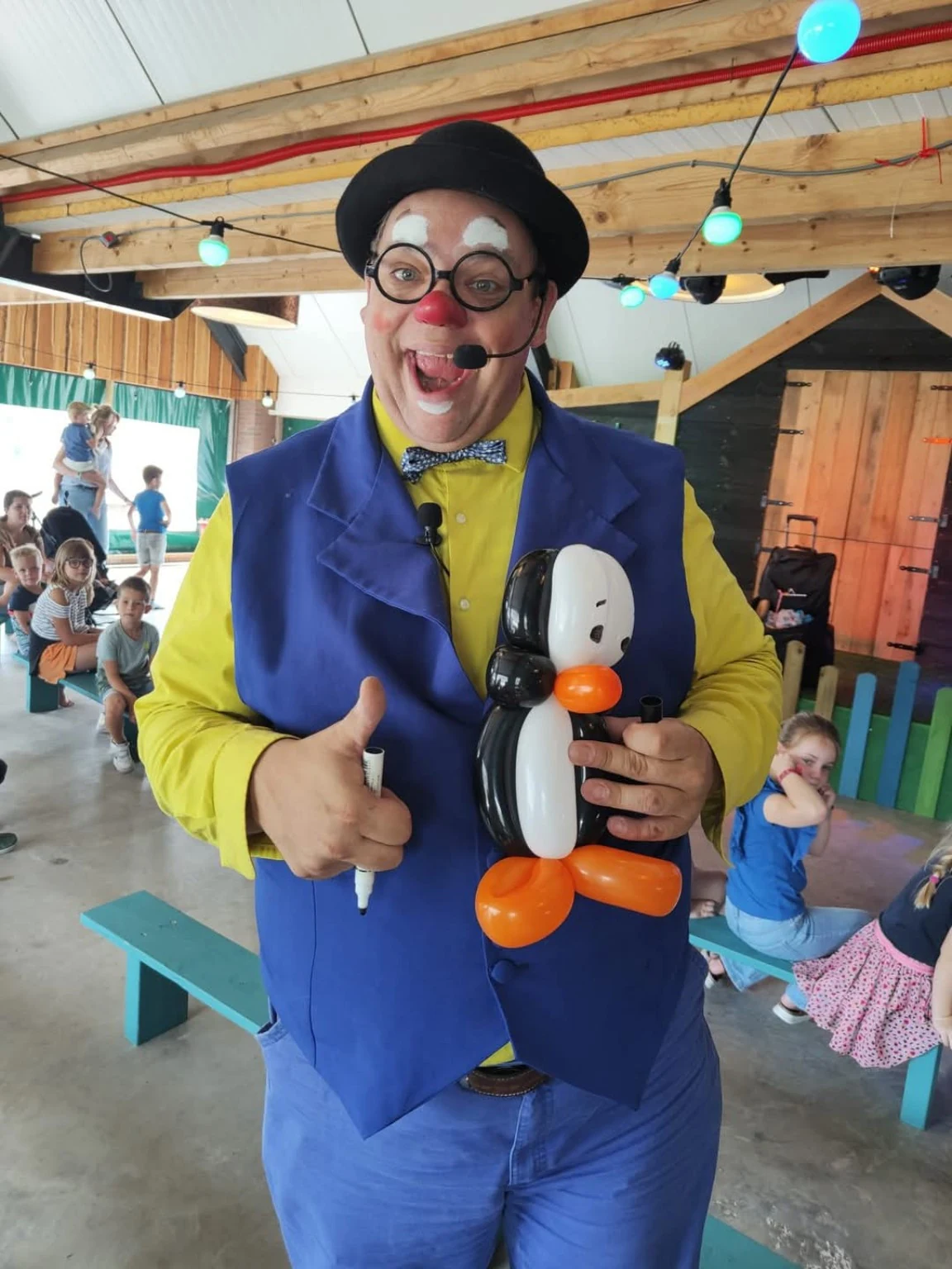 Clown Spekkie met een ballonfiguur tijdens een kinderactiviteit