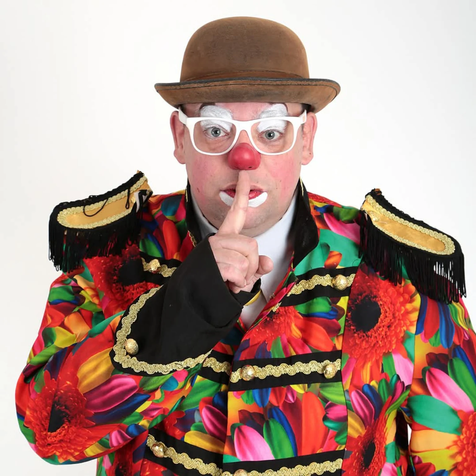 Clown Spekkie maakt een stilgebaar naar de camera